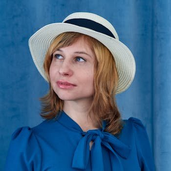 Elegant portrait of a woman in a straw hat against a blue background.